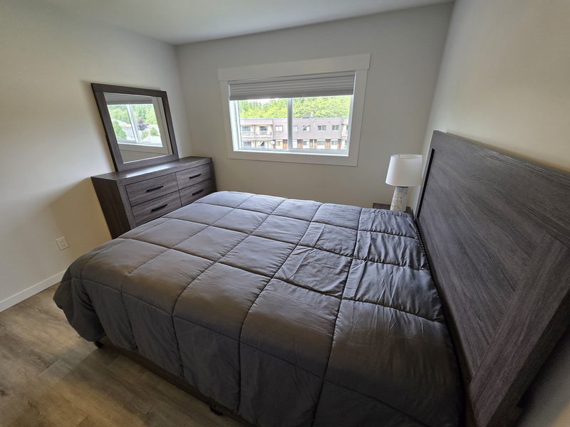Chambre meublée avec lit double, commode et fenêtre