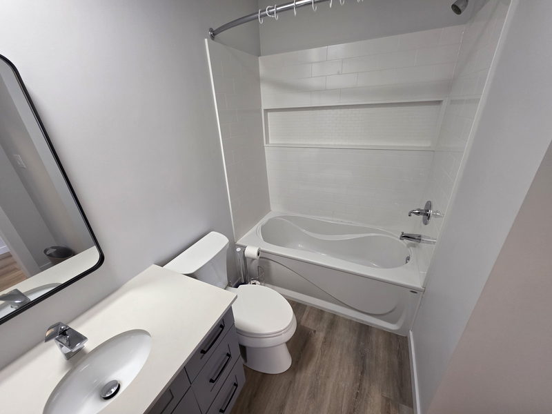 Salle de bain rénovée avec baignoire, vanité et entourage carrelé
