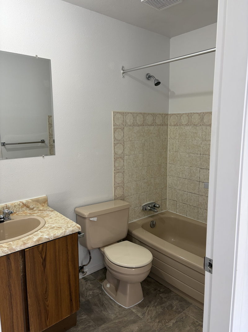 Salle de bain avec entourage de baignoire carrelé et vanité en bois